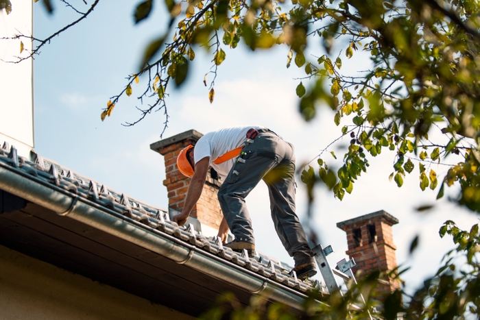 Roofer measuring chimney on roof top