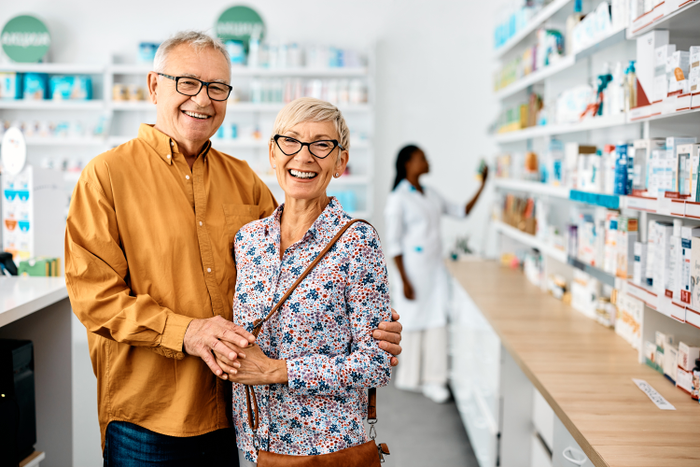 Portrait of happy senior couple in drugstore looking at camera.