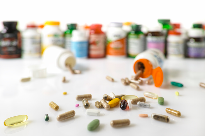 Many nutritional health supplements and vitamins in capsules, tablets and in bottles on a white background, shallow depth of focus.