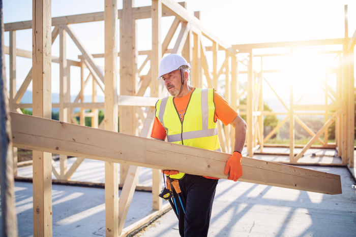 Builder Working On Wooden House