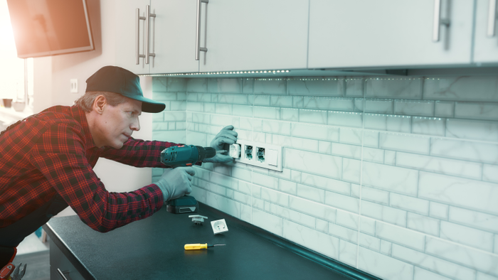 man in uniform holding a drill and installing new socket box