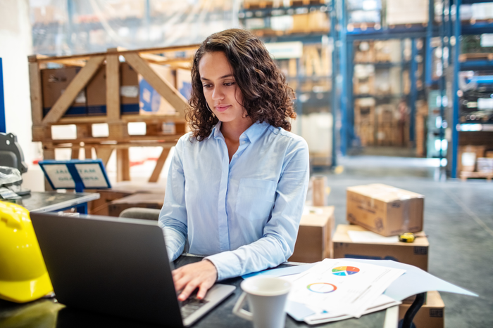 false Businesswoman updating stocks on laptop at warehouse