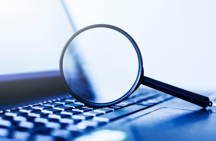 Laptop computer with magnifying glass, concept of search