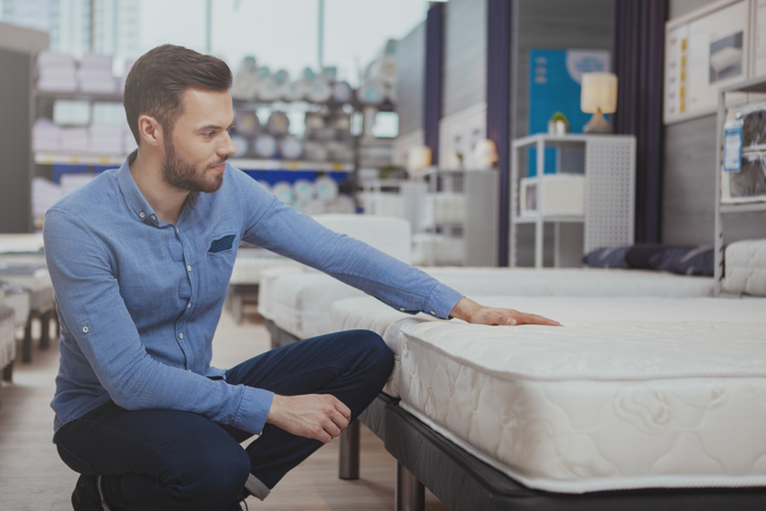 Man examining mattress on sale at furniture store